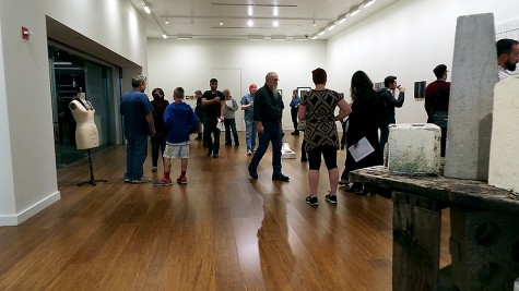 A group of people viewing the Faculty Art Exhibit at College of DuPage on Nov, 6, 2014. The art exhibit displayed multiple different art forms, from paintings to sculptures. 