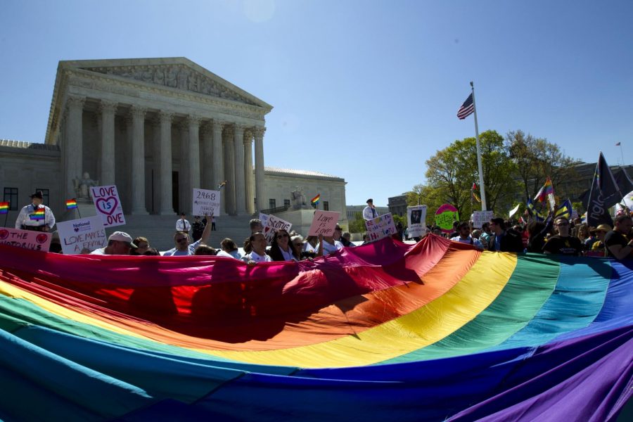 In this April 28, 2015 file photo, demonstrators stand in front of a rainbow flag of the Supreme Court in Washington as the Supreme Court was set to hear historic arguments in cases that could make same-sex marriage. 