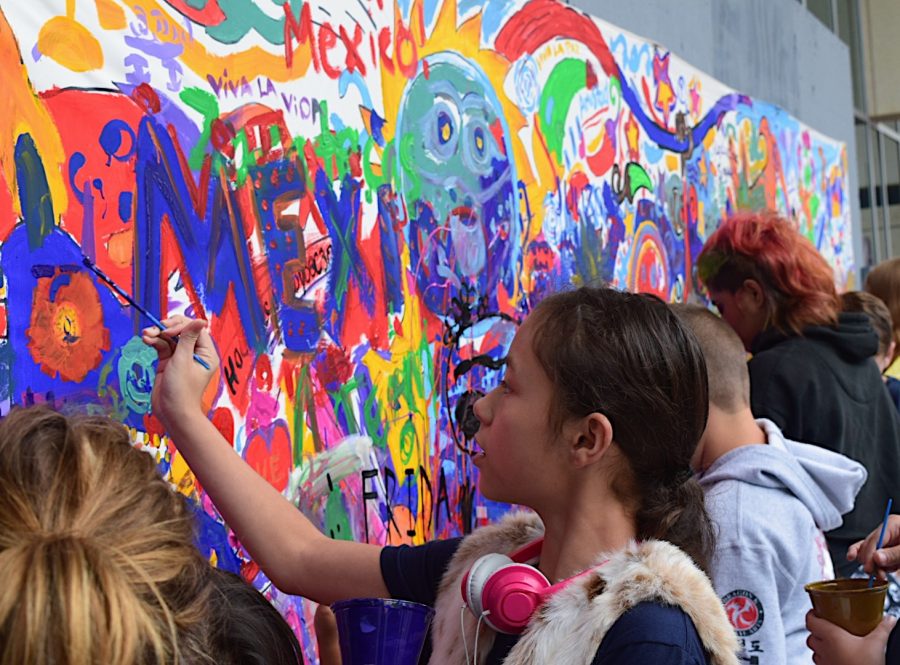 Adults and children alike gathering to contribute to the community mural.