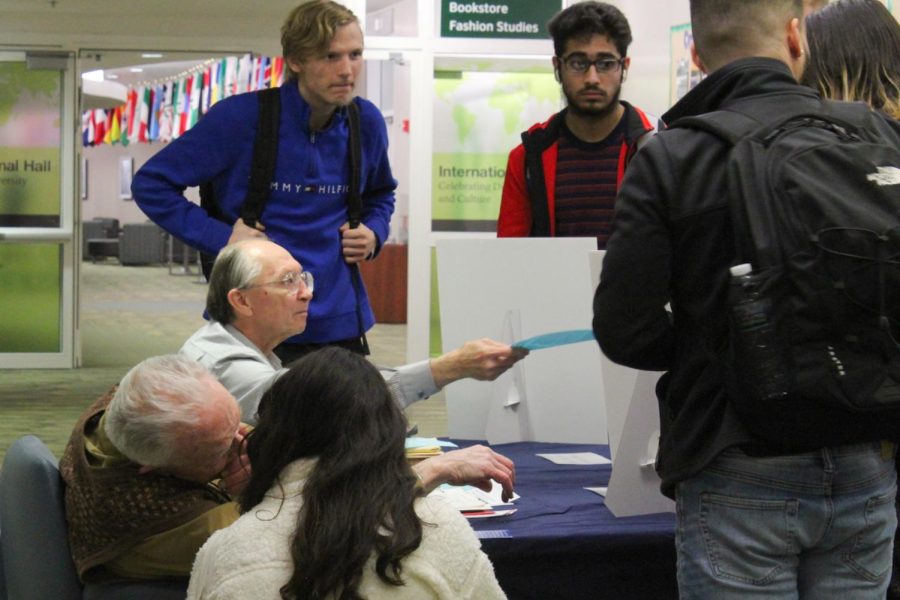 Wayne Lela hands a flyer to a student