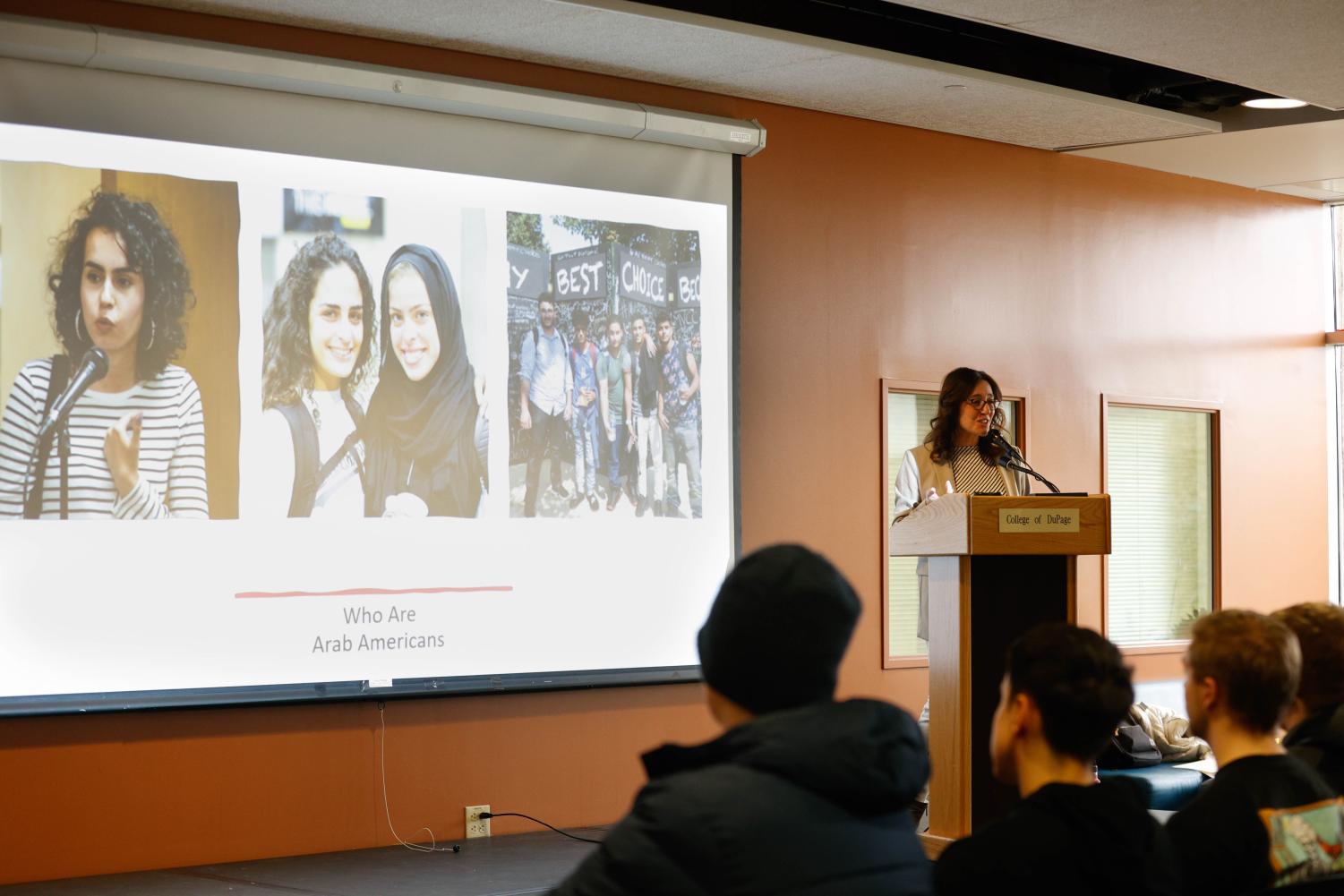 Souzan Nasser speaks to COD students, staff and faculty. A slide in the background shows the text "Who are Arab Americans?"