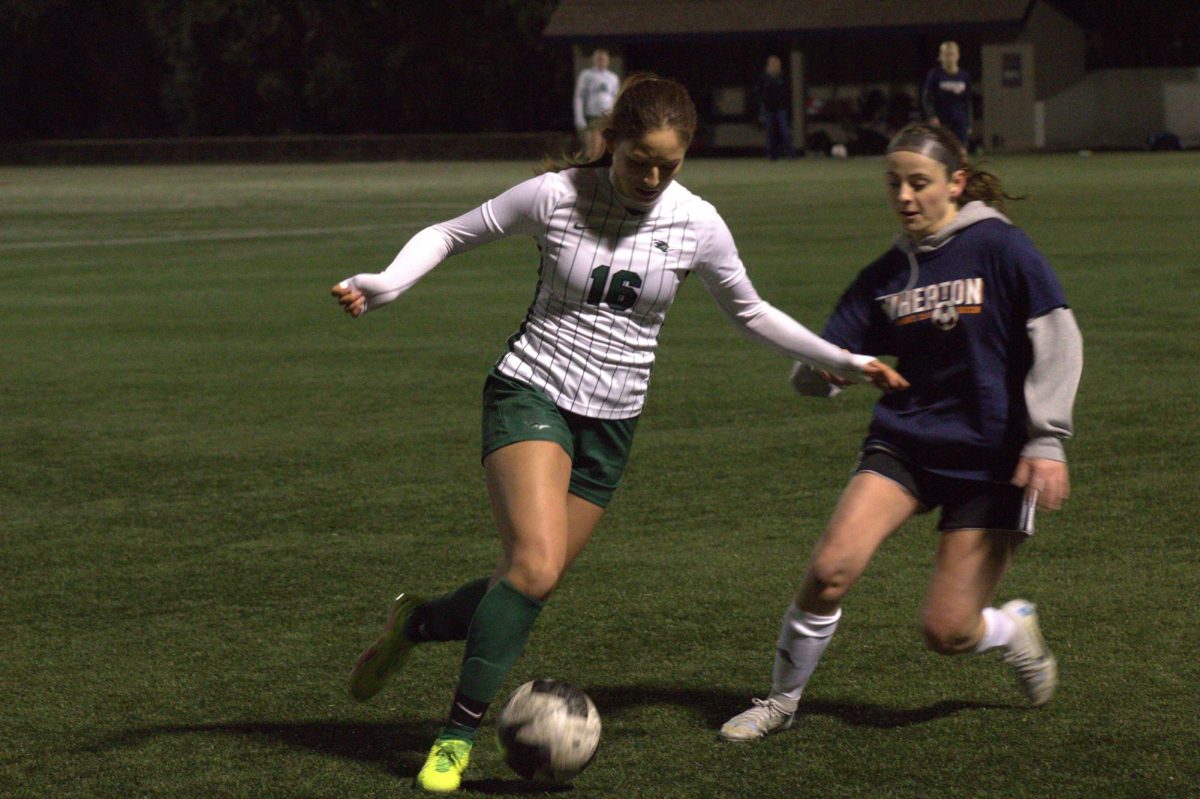 Sophomore Alyssa Arce dribbles past a Wheaton College defender after gaining possession.