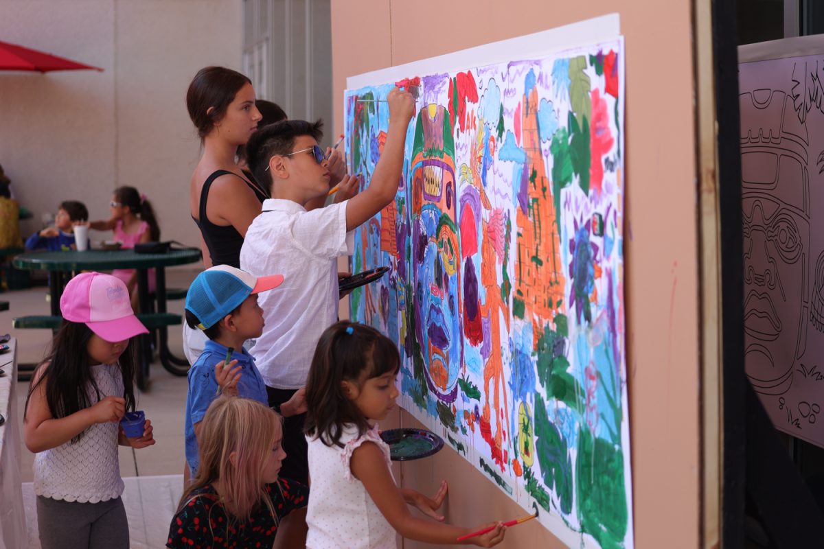 Event attendees paint a mini mural at the Olmec Family Fiesta. 
