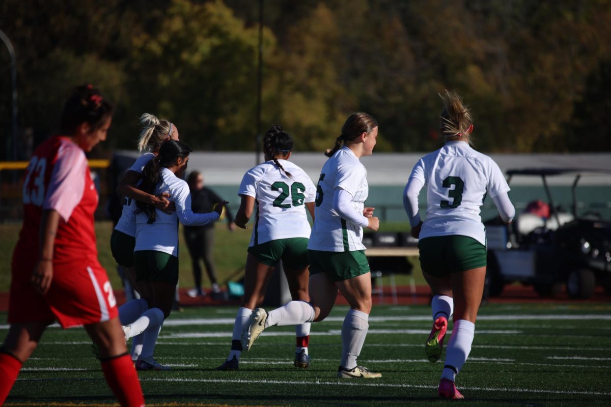 The COD women's soccer team celebrates after scoring a goal.