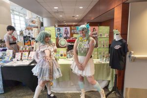 An artist booth with workers in cosplay.