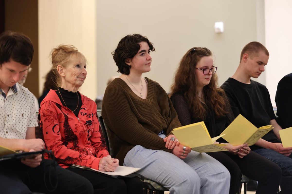 Students listening to speakers during Alpha Mu Gamma induction ceremony.