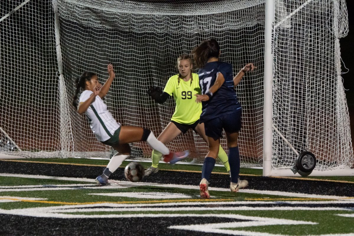 Number 26, Annabelle Andino and Number 99, Elizabeth Fried attempting to block the ball from an attacking player.